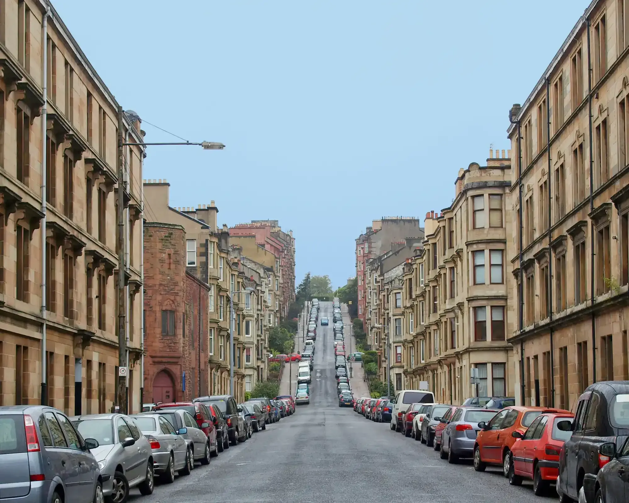 A row of traditional sandstone tenement buildings on a residential street in Glasgow