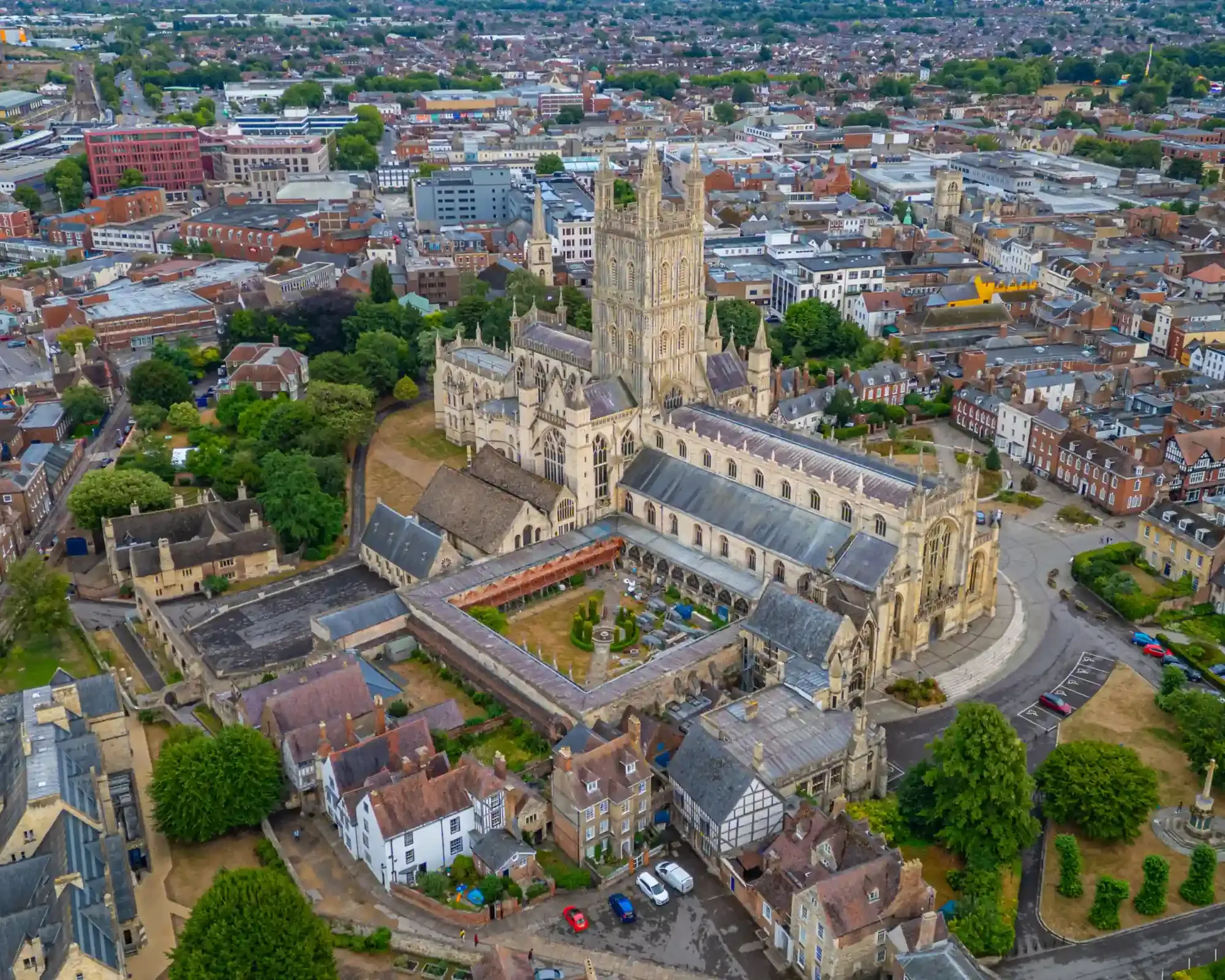 Aerial view of Gloucester Cathedral and its cloisters, surrounded by the historic streets of Gloucester city centre.