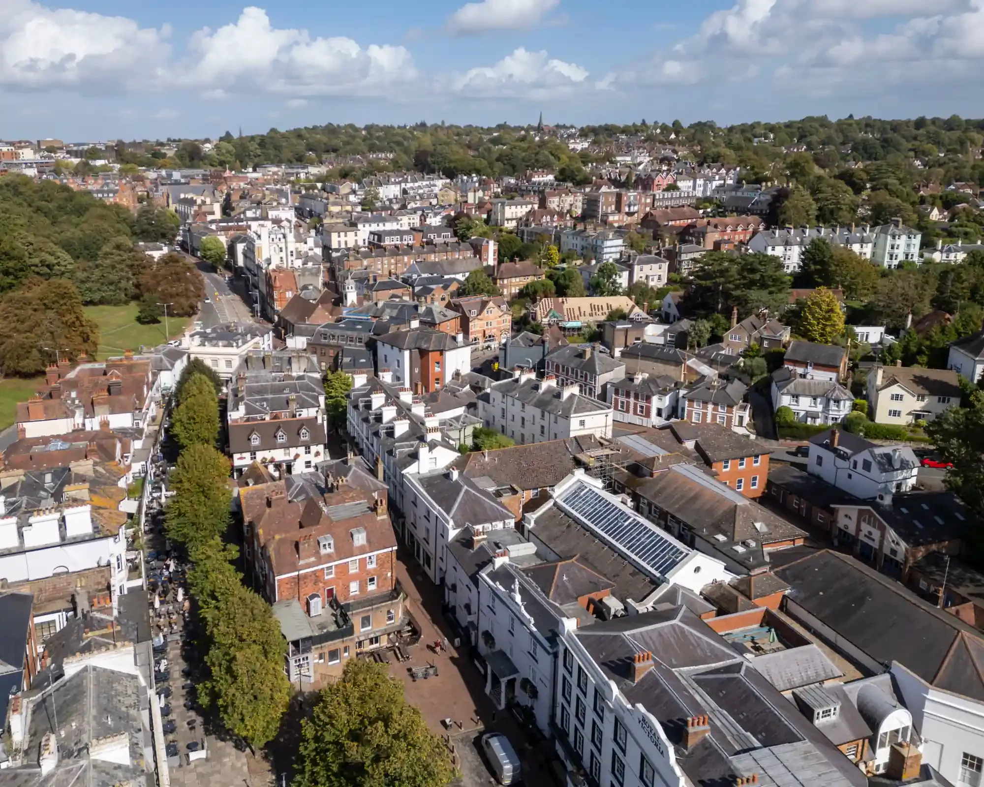 Aerial view of The Pantiles in Tunbridge Wells, with its tree-lined colonnade and period buildings, and the town spreading out behind.
